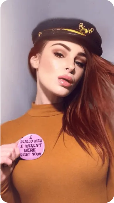 Red haired creator poses with sailor hat, yellow turtleneck, and pink pin from Hot Topic